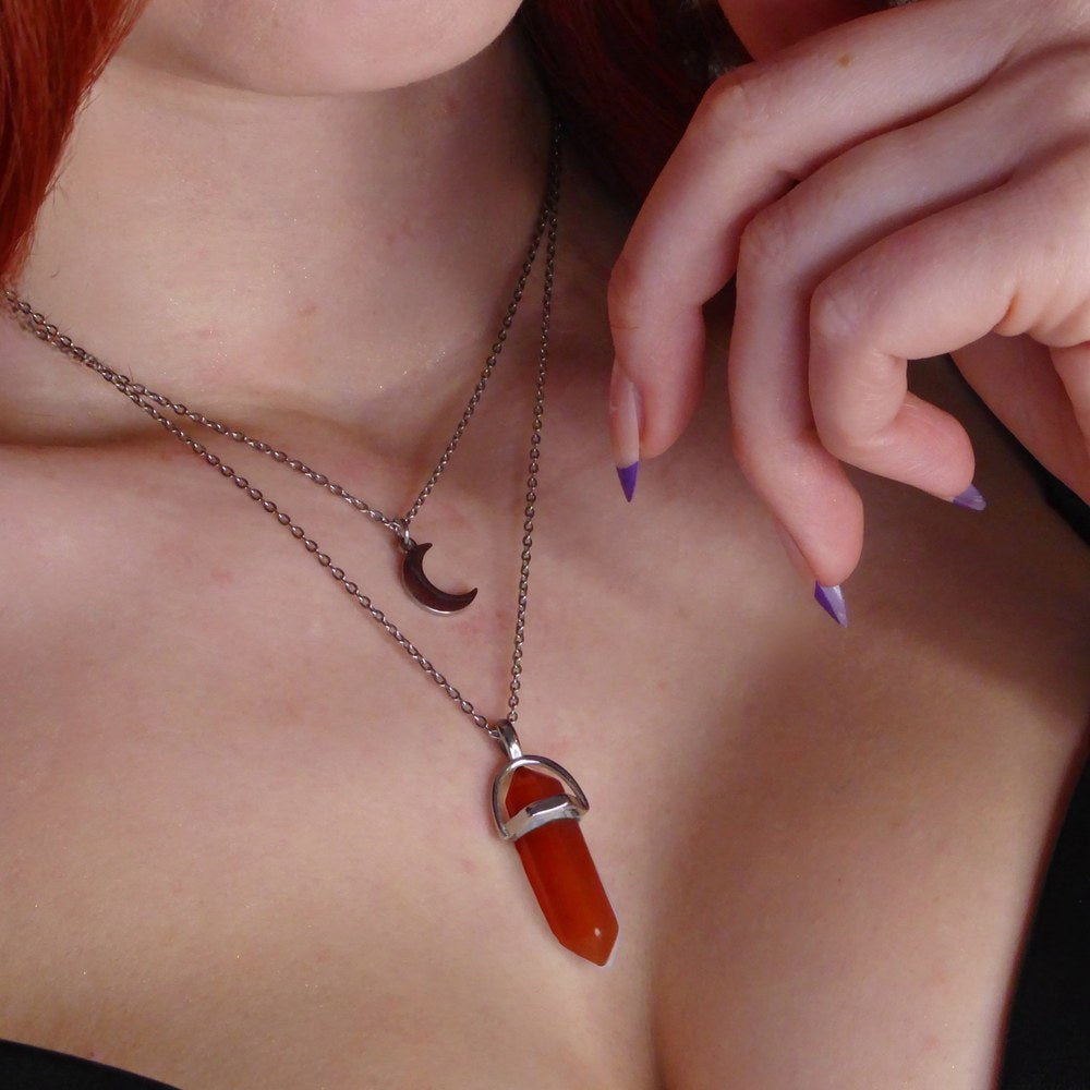 The Pomence Carnelian Attraction Necklace worn in the Silver colorway, the carnelian point in its silver stirrup bail on the longer chain and the silver crescent moon charm on the shorter chain