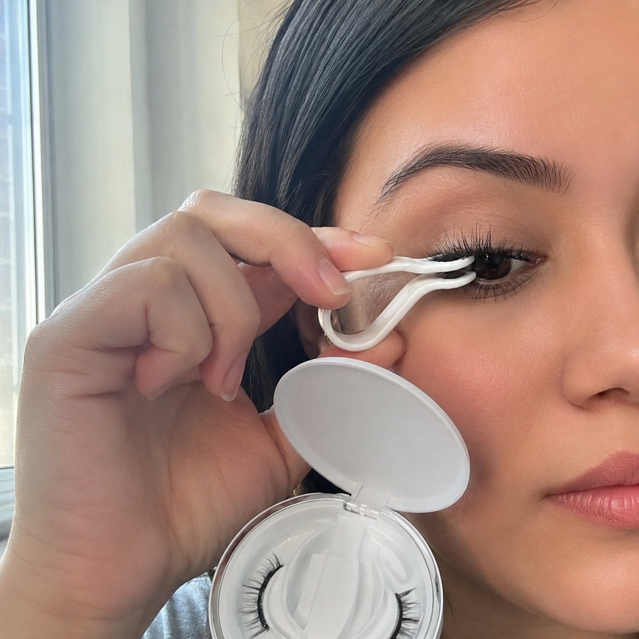 Hand pressing a Pomence magnetic lash into place with the applicator