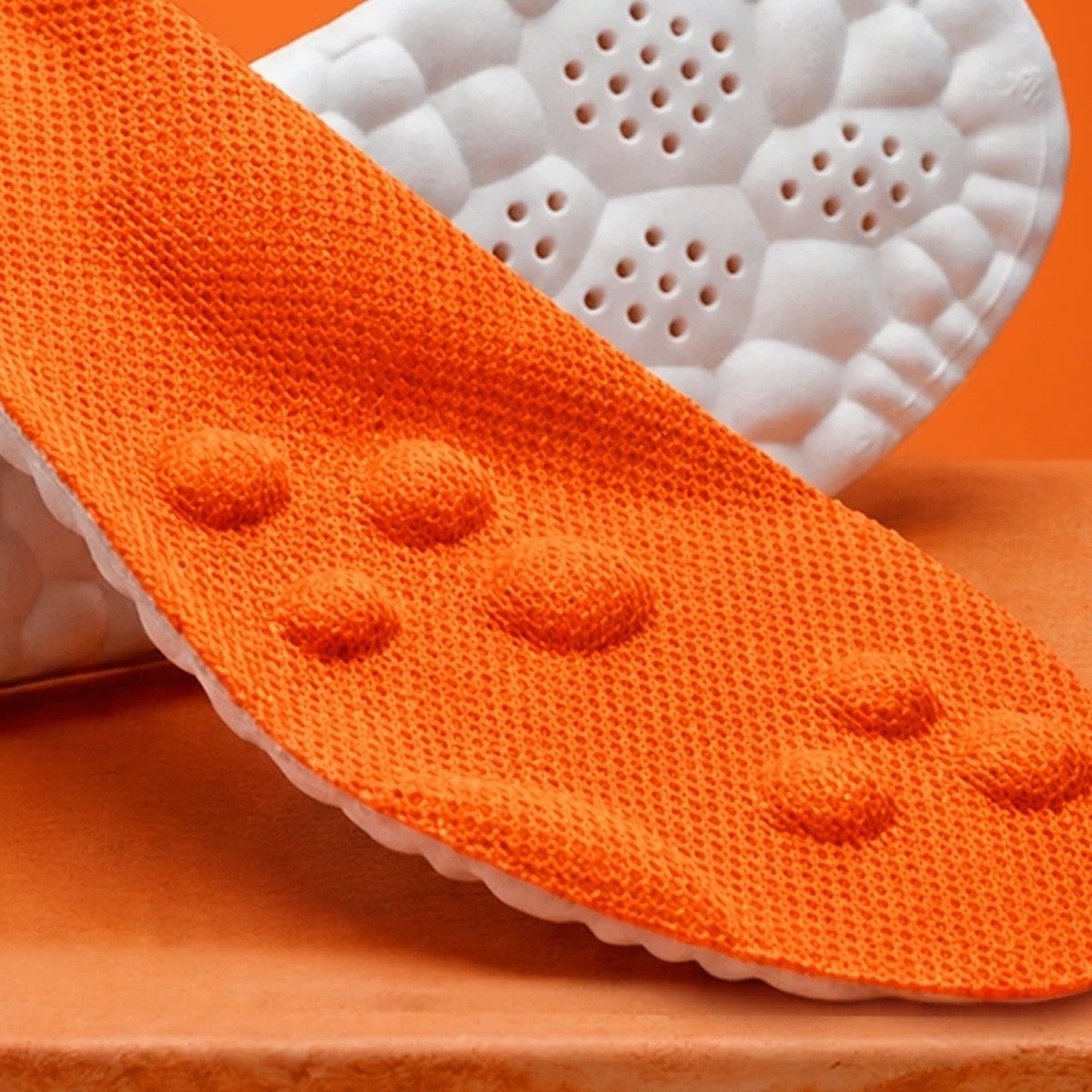 A pair of black Pomence Massage Insoles, one turned over to show the white cobblestone shock-absorbing base
