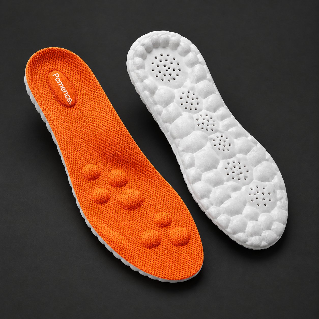 A pair of Pomence Massage Insoles on a dark ground