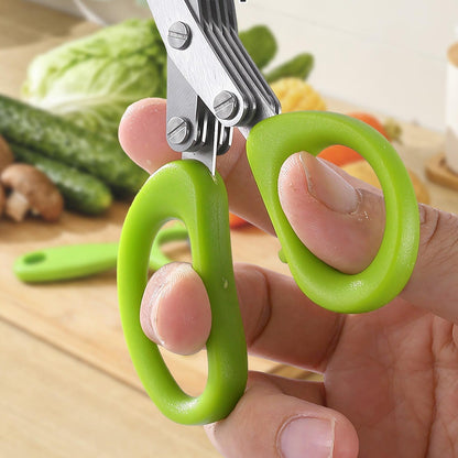 The listing's own photo: a hand through the green non-slip loops, the blades above, a kitchen counter with vegetables behind (cut below its drawn heading)