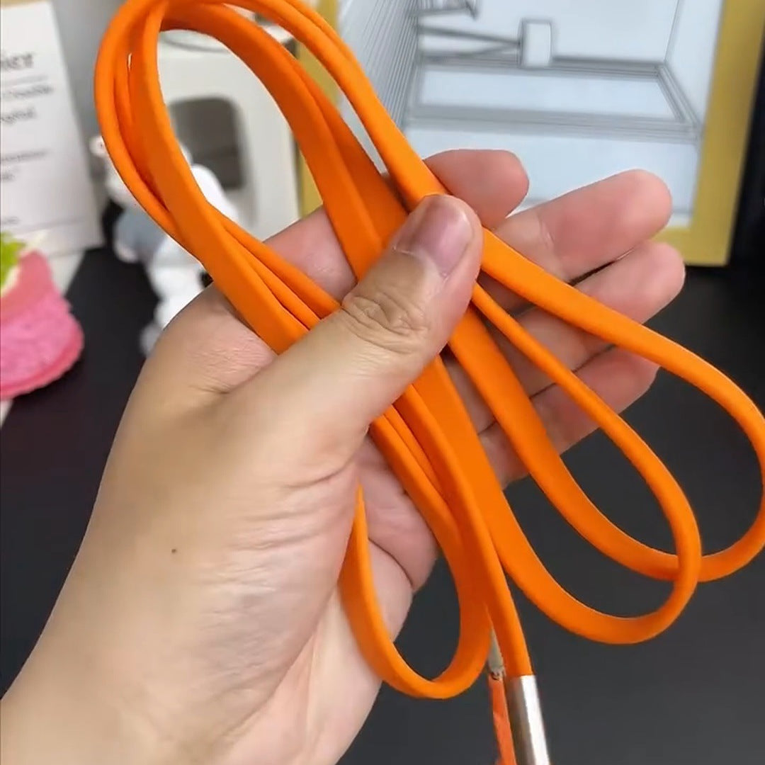 real hand holding the coiled orange braided cable with its plug, desk behind
