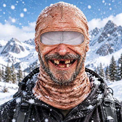 The Uncle mask worn in the snow: bald, stubble beard, wide gap-toothed grin, mountains behind.