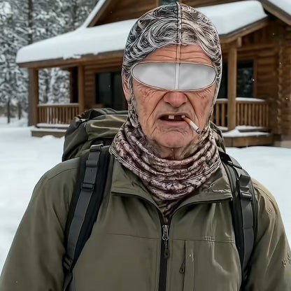 A man in an olive jacket and backpack wearing the Grandma mask in front of a snowy log cabin.