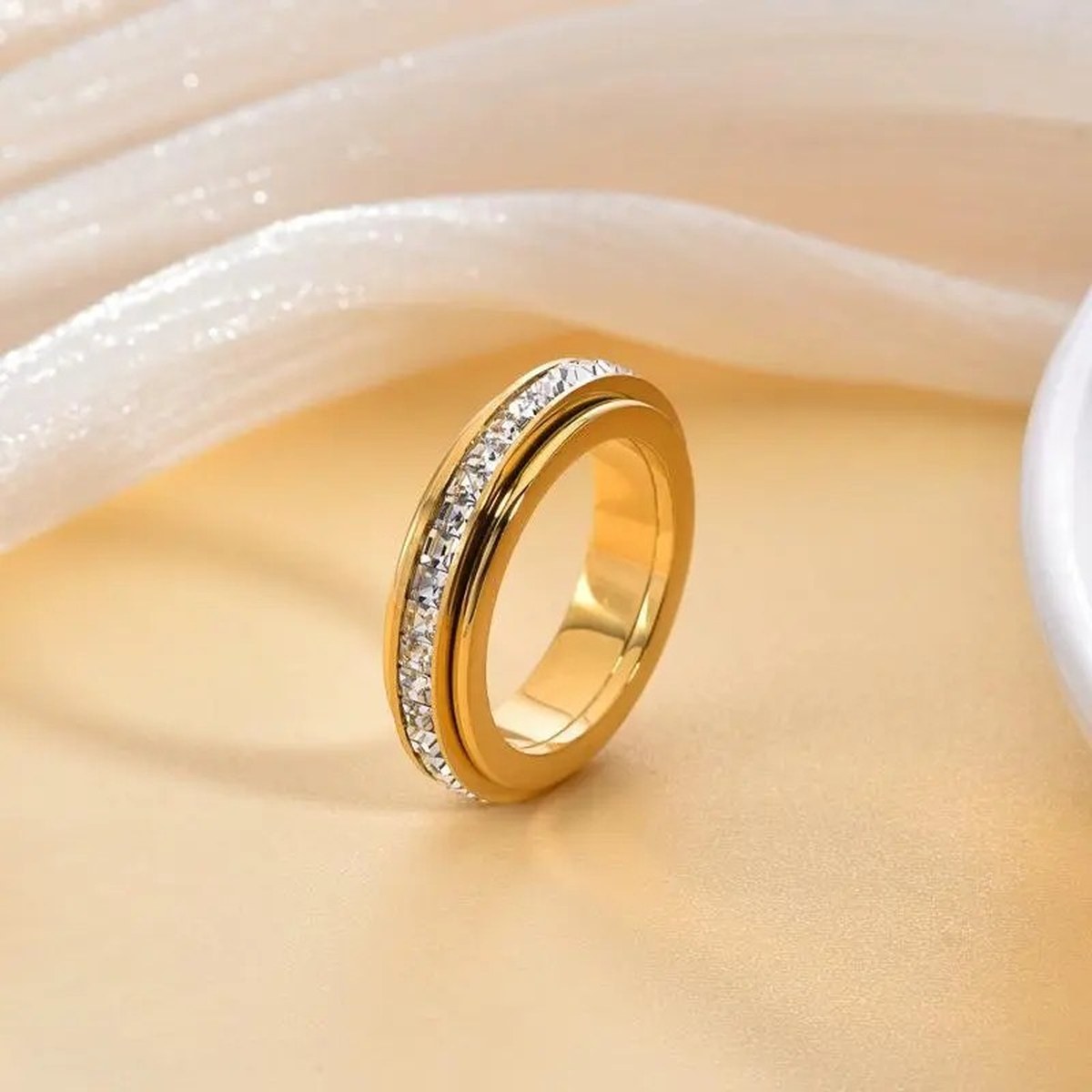 Pomence™ Anxiety Spinner Ring. Golden: spinner ring resting on cream silk