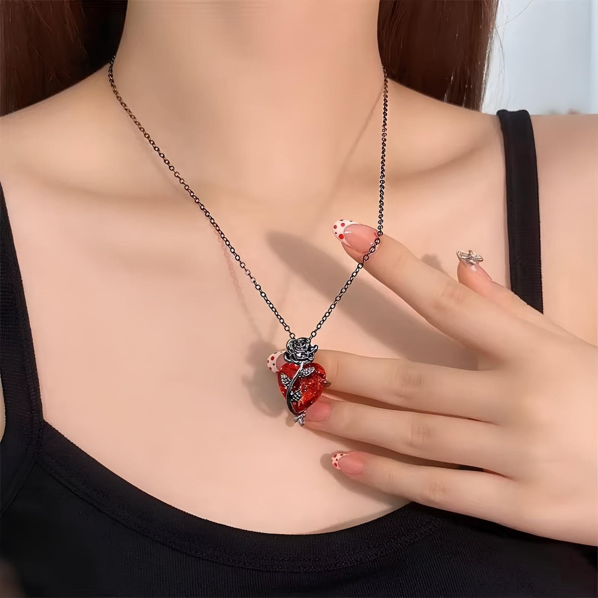 Pomence Blood Rose Necklace worn, a hand beside the red heart pendant