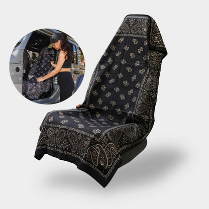 The Pomence Car Seat Cover Towel in Black Paisley over a car seat, and a woman slipping it on