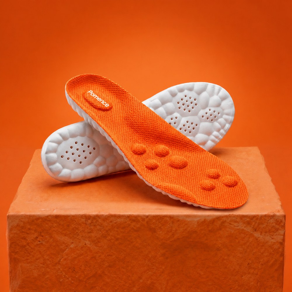 A pair of Pomence Massage Insoles, orange knit deck up and white cobblestone base up, on an orange plinth