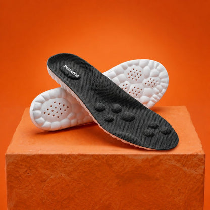 A pair of Pomence Massage Insoles in black, the black knit deck with its massage nodes and the white cobblestone base