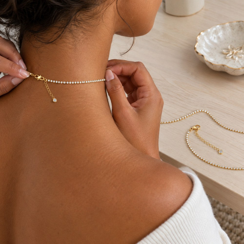 The Pomence Tennis Necklace worn at a vanity with the lobster clasp and 2 inch extender laid open beside it