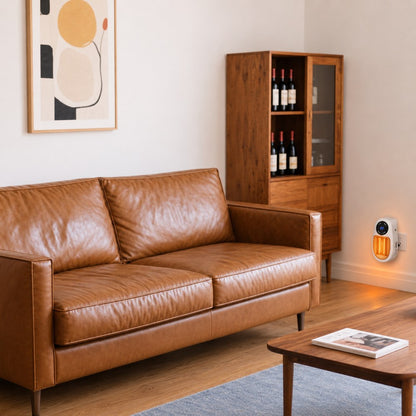 The Pomence Wall Outlet Heater plugged into the wall beside a leather sofa, its LED display showing 22