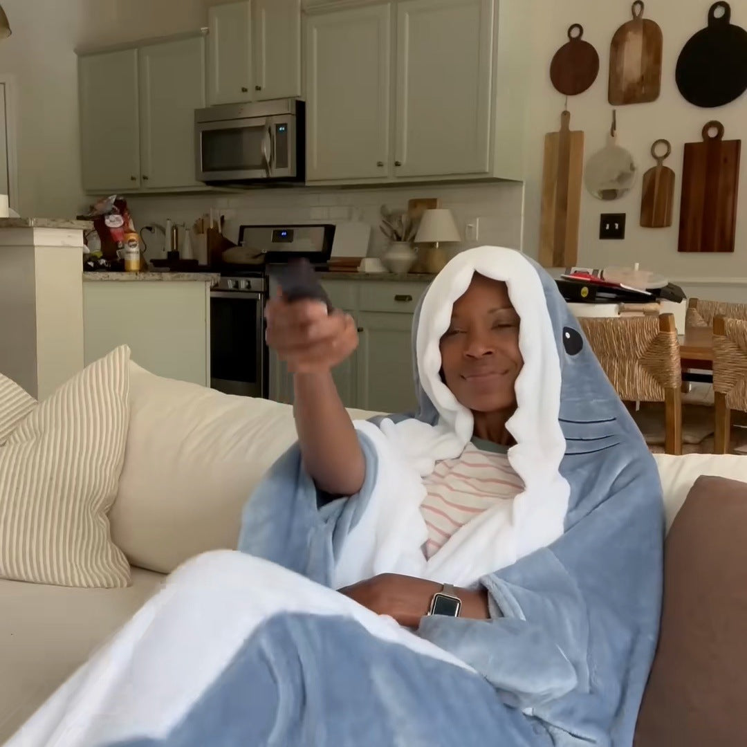 a woman lounging on a white sofa wrapped in the shark, hood up, legs inside