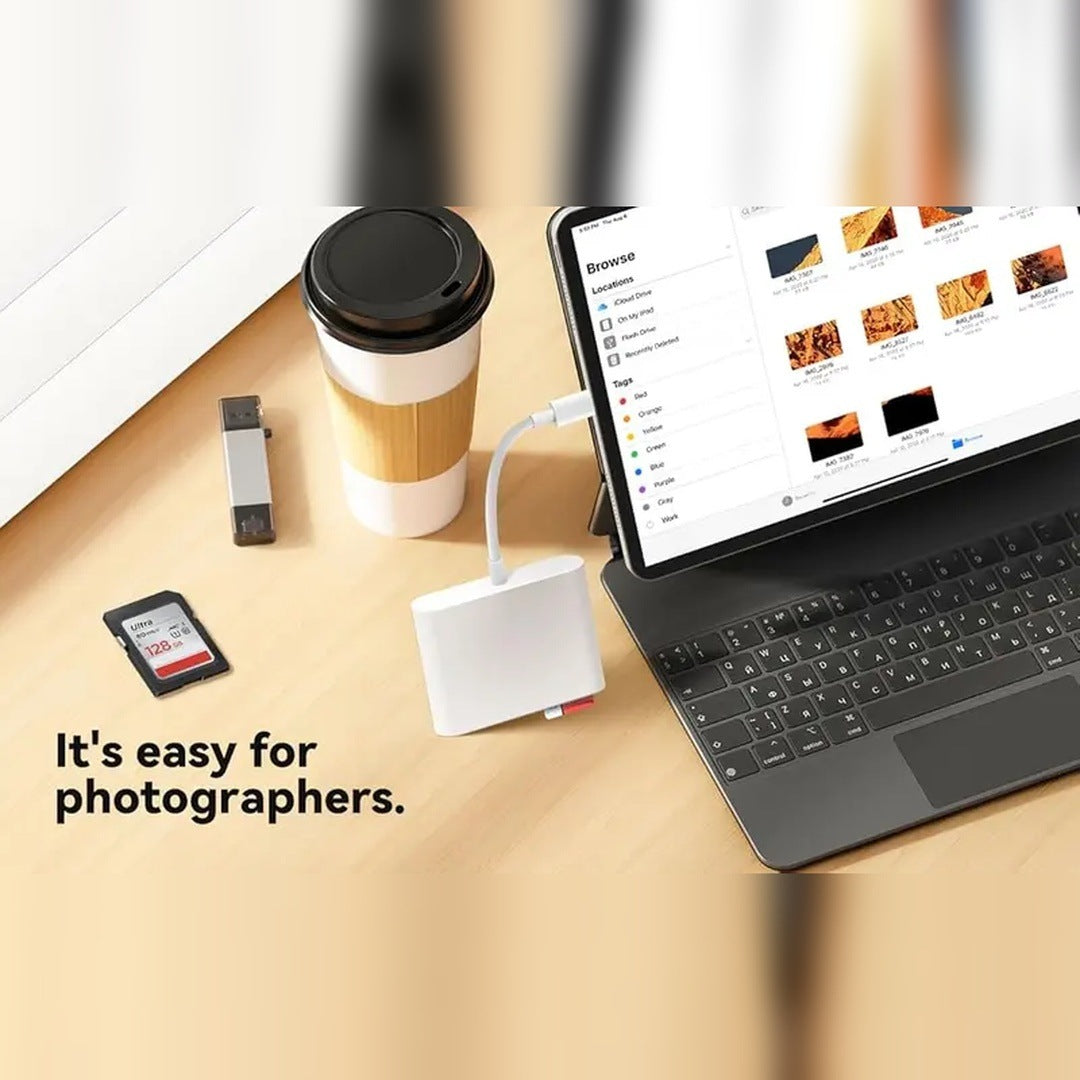 The listing's own photo: the reader plugged into a USB-C iPad on its short cable with an SD card in, a keyboard folio and a coffee cup beside it, warm wood desk.