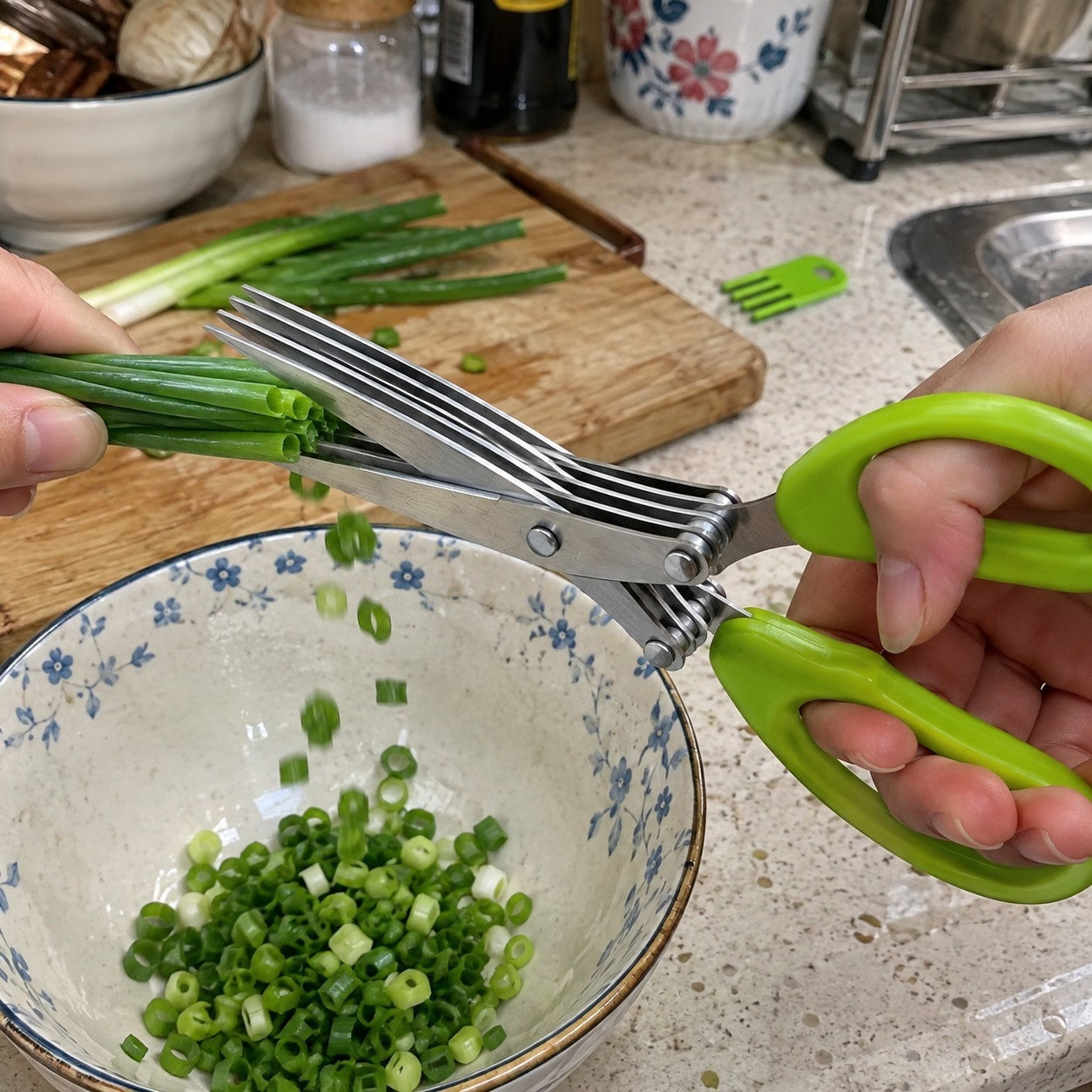 Hand snipping green onions over a bowl