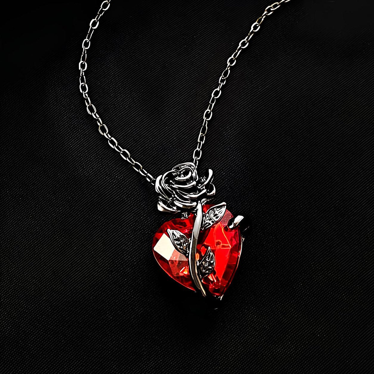 The thorned stem and two leaves crossing the face of the red heart