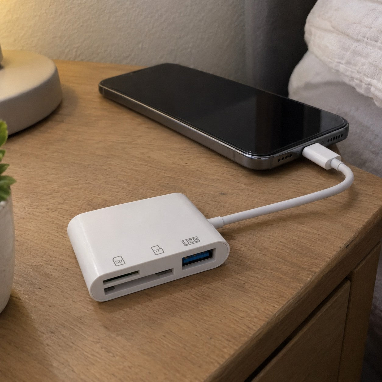 Phone and reader on a bare nightstand, plug going in