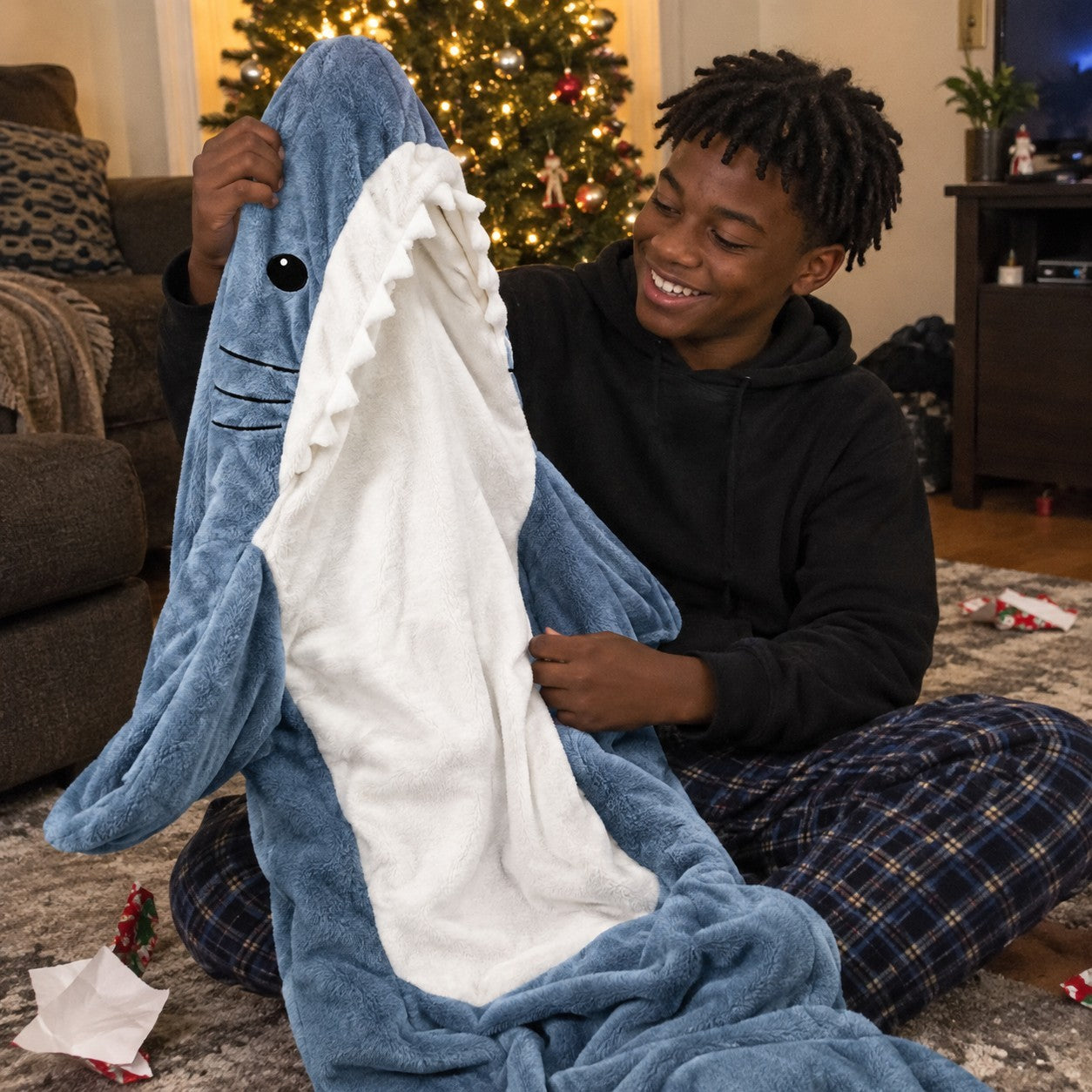 Teen boy pulling a shark blanket from gift wrap