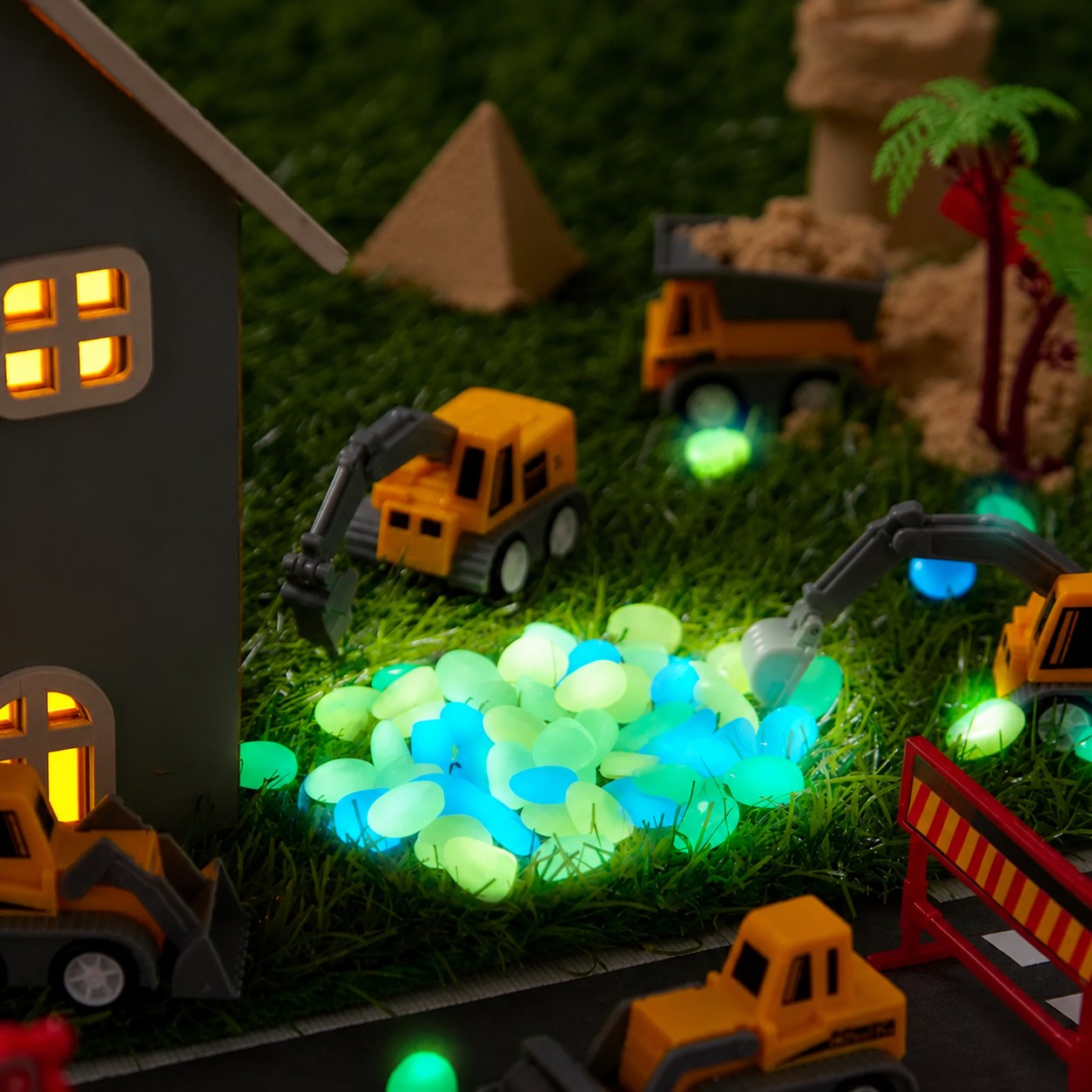 Glow-in-the-dark stones lighting up a construction scene with toy trucks at night