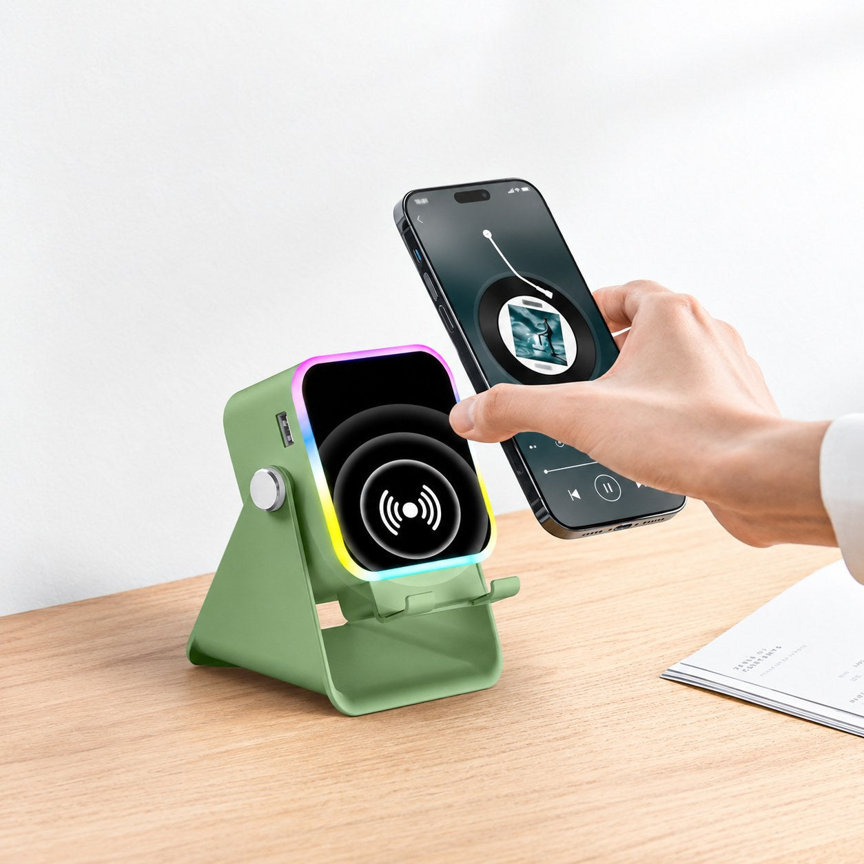 A hand setting a phone onto the green Pomence Speaker Phone Stand on a wooden desk