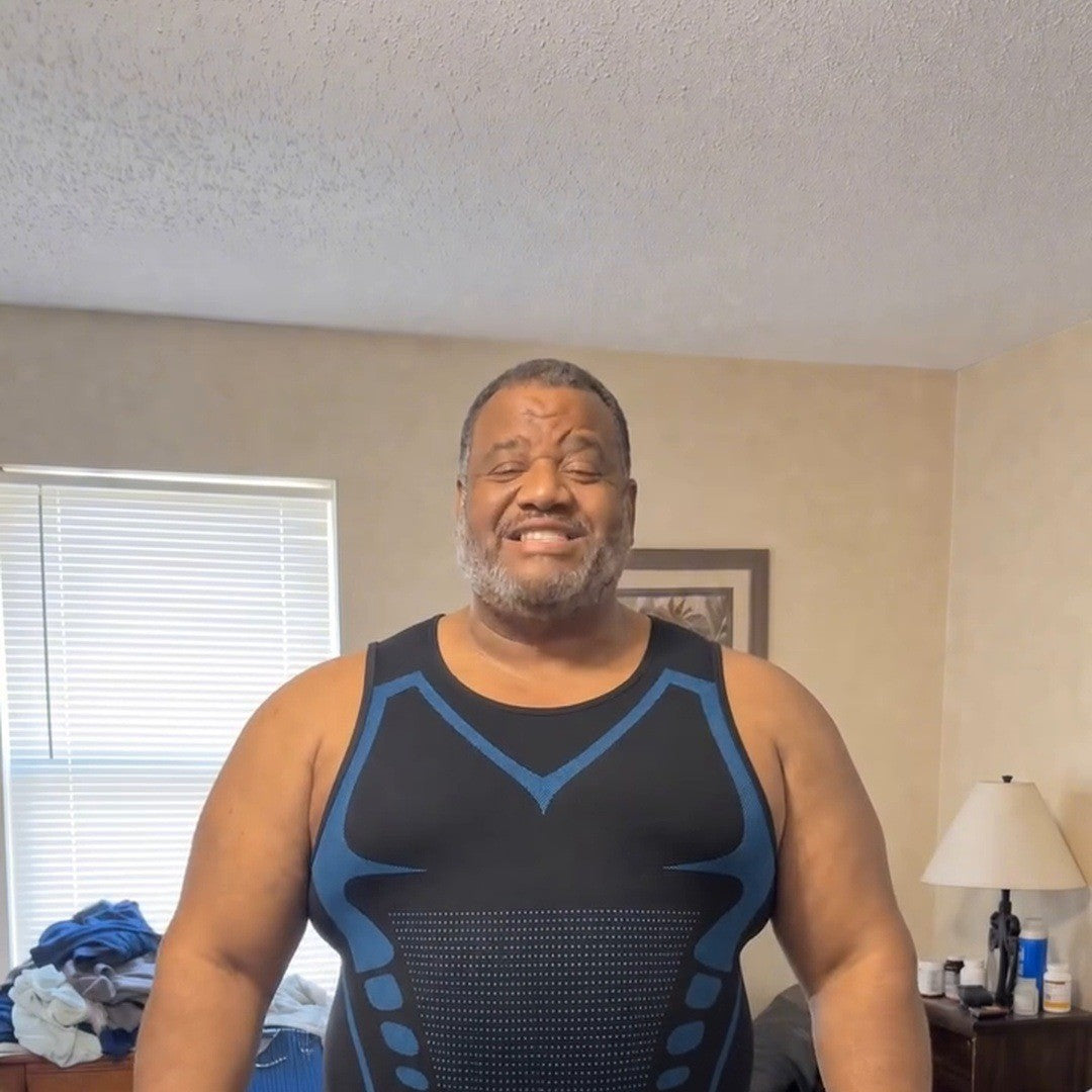 Big man in his bedroom standing tall in the black tank