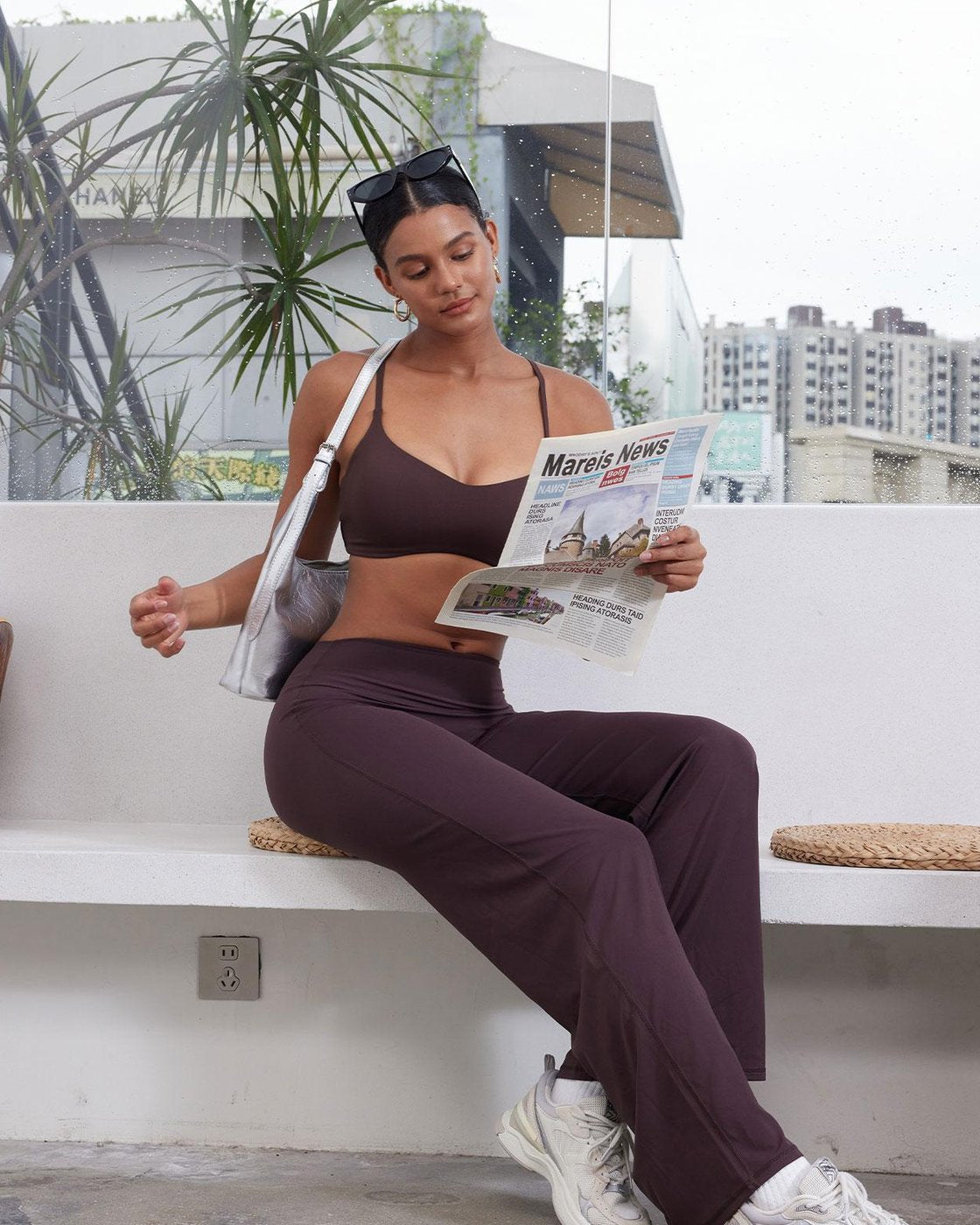 A woman sitting on a bench reading a newspaper in Pomence high-waisted straight leg yoga leggings